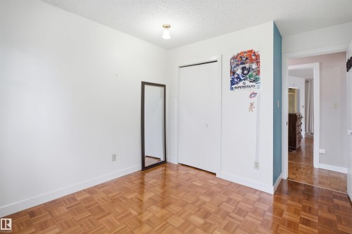 Room featuring wood-finish parquet flooring, white walls, and a built-in closet with bi-fold doors - 3220 42A Avenue, Edmonton, AB 