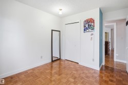 Room featuring wood-finish parquet flooring, white walls, and a built-in closet with bi-fold doors - 