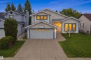 Two-story detached residence featuring light-colored siding, a two-car garage with a white door, and contrasting blue trim accents - 3220 42A Avenue, Edmonton, AB 