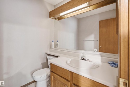 Bathroom vanity featuring a built-in sink, laminate countertop, wood-finish cabinetry, and an overhead light fixture - 3220 42A Avenue, Edmonton, AB 