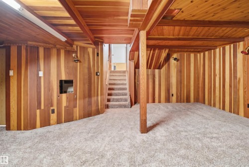Finished lower level featuring vertical wood-paneled walls and ceiling beams - 3220 42A Avenue, Edmonton, AB 