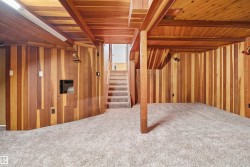 Finished lower level featuring vertical wood-paneled walls and ceiling beams - 