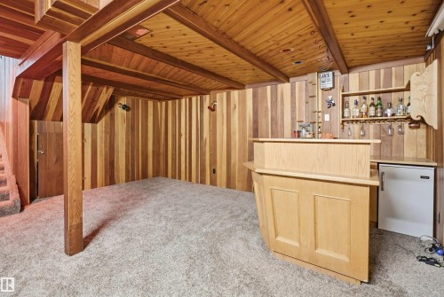 Recessed bar area with light wood paneling, built-in shelving, and a compact refrigerator - 3220 42A Avenue, Edmonton, AB 
