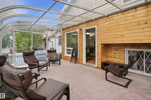 Curved glass sunroom with a wood-paneled wall and light-toned carpeting - 3220 42A Avenue, Edmonton, AB 