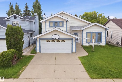 Two-story home with light-toned siding, a two-car garage, and a concrete driveway - 3220 42A Avenue, Edmonton, AB 