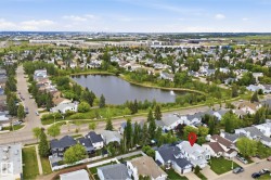 Residential neighborhood featuring a prominent pond with a fountain, surrounded by mature trees and paved roads - 