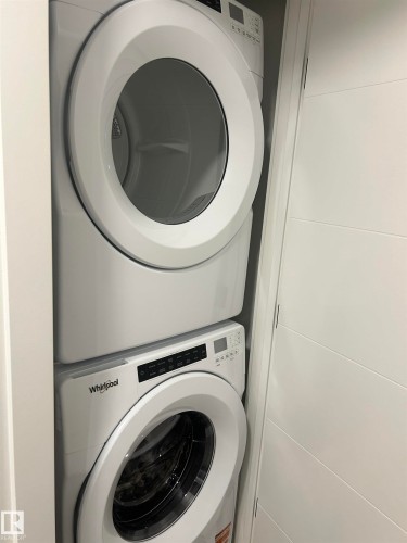Dedicated laundry alcove featuring a white stackable washer and dryer unit - 11012 132 Street, Edmonton, AB 