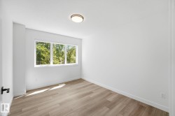 Room featuring light wood-finish flooring, white walls, and a large multi-pane window - 