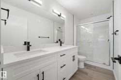Bathroom featuring a dual vanity with white cabinetry, integrated sinks, and black hardware - 