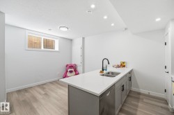 Kitchenette featuring a dual-basin stainless steel sink, matte black faucet, and white countertop - 