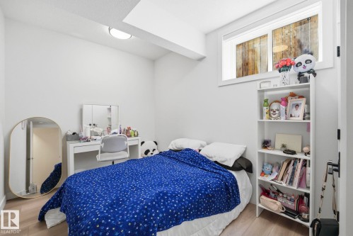 Room featuring wood-finish flooring, white walls, and a large window - 11012 132 Street, Edmonton, AB 