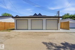 Detached three-car garage featuring white siding and individual overhead doors - 