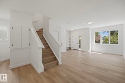 Open-concept living area with wood-finish flooring, white walls, and recessed lighting - 