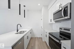 Modern kitchen featuring white cabinetry, quartz countertops, and stainless steel appliances - 
