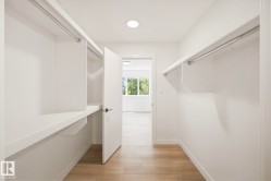 Walk-in closet with integrated shelving, hanging rods, and light wood-finish flooring - 