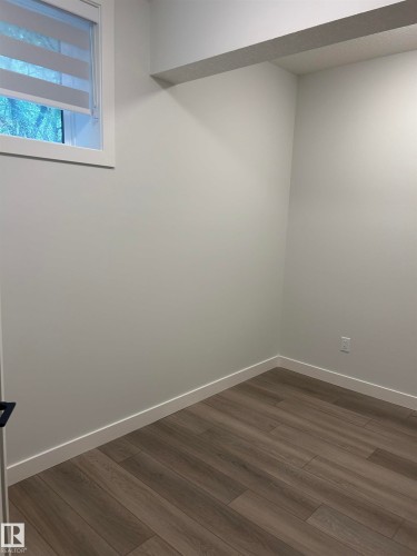 Neutral wall tones, wood-finish flooring, white trim, and a window with blinds provide a clean interior aesthetic - 11007 132 Street, Edmonton, AB 
