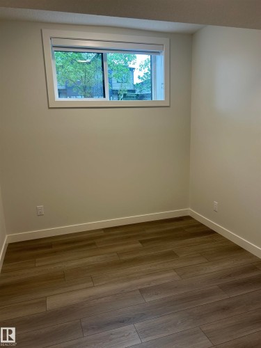 Room with wood-finish flooring, white baseboards, and a window with white trim - 11007 132 Street, Edmonton, AB 