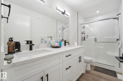 Dual sink vanity with white cabinetry, integrated sinks, and dark-finish fixtures - 