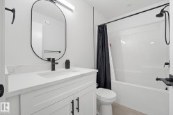 Bathroom featuring a single vanity with stone-finish countertop, undermount sink, and matte black faucet - 