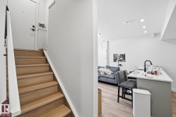 Hardwood staircase with white risers and handrail leading to an entryway with a white door - 