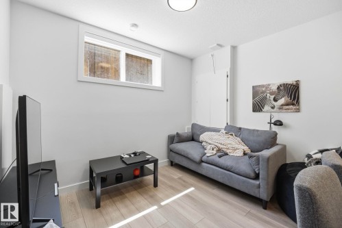 Finished basement living space featuring light wood-finish flooring, a contemporary window, and recessed lighting - 11007 132 Street, Edmonton, AB 