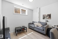 Finished basement living space featuring light wood-finish flooring, a contemporary window, and recessed lighting - 