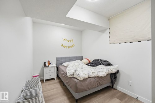 Room featuring wood-finish flooring, recessed lighting, and a window with a roller shade - 11007 132 Street, Edmonton, AB 