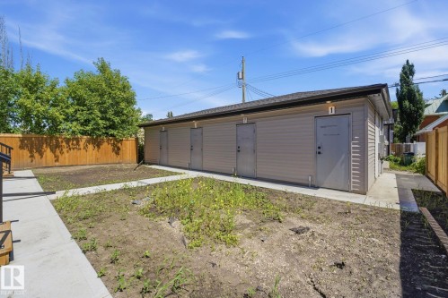 Building exterior featuring beige siding, multiple entry doors with overhead lighting, and a dark shingle roof - 11007 132 Street, Edmonton, AB 