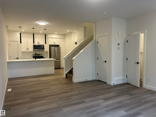 Open-concept living space with wood-finish flooring extending into the kitchen - 11007 132 Street, Edmonton, AB 
