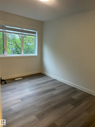 Interior space with wood-finish flooring, white baseboards, and neutral wall paint - 11007 132 Street, Edmonton, AB 