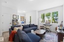 Spacious room featuring wood-finish flooring, a large window with exterior greenery, and recessed lighting - 11007 132 Street, Edmonton, AB 
