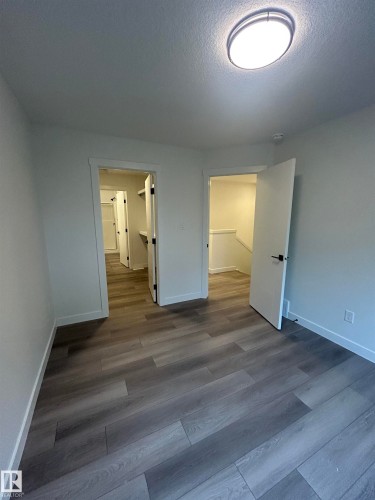 Room featuring wood-finish flooring, white walls, and a flush-mount ceiling light - 11007 132 Street, Edmonton, AB 