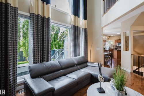 Two-story living area with expansive windows, wood-finish flooring, and an upper-level balcony overlooking the space - 5206 Cercle Ciel Crescent, Beaumont, AB 