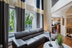 Two-story living area with expansive windows, wood-finish flooring, and an upper-level balcony overlooking the space - 