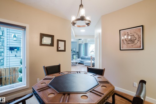 Dining area featuring hardwood flooring, a contemporary chandelier, and a large window - 5206 Cercle Ciel Crescent, Beaumont, AB 