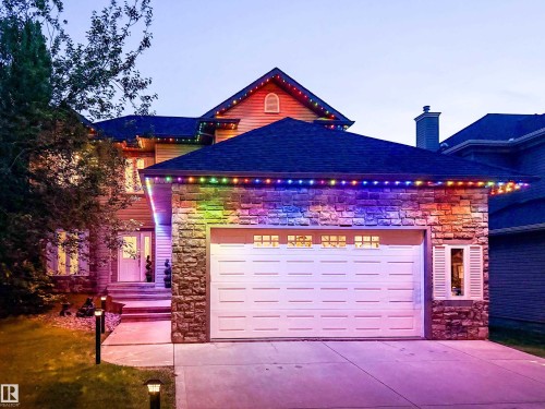 Stone facade residence featuring a two-car garage, concrete driveway, and covered front entry - 5206 Cercle Ciel Crescent, Beaumont, AB 