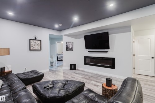 Recessed lighting illuminates a contemporary entertainment area featuring a built-in linear electric fireplace - 5206 Cercle Ciel Crescent, Beaumont, AB 