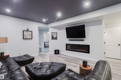 Recessed lighting illuminates a contemporary entertainment area featuring a built-in linear electric fireplace - 