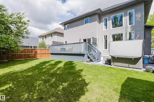 Expansive backyard featuring a manicured lawn, a full wooden privacy fence, and a multi-level deck with steps - 5206 Cercle Ciel Crescent, Beaumont, AB 