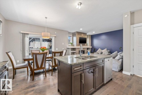 Central kitchen island featuring a dual-basin stainless steel sink, granite countertop, and dark wood cabinetry - 4105 171A Avenue, Edmonton, AB 