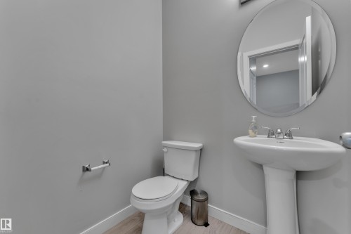 Pedestal sink with chrome fixtures and an oval frameless mirror - 9328 Pear Link Link, Edmonton, AB 
