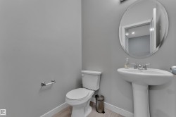 Pedestal sink with chrome fixtures and an oval frameless mirror - 