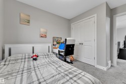 Bedroom featuring neutral gray wall paint, light gray carpeting, and a white paneled headboard - 