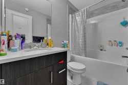Bathroom featuring a vanity with a white countertop and dark wood-finish cabinetry, an integrated sink with a chrome faucet, and a combined bathtub and shower unit - 
