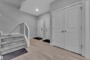 Entryway featuring wood-finish flooring, a carpeted staircase with a white railing, and a double-door closet - 9328 Pear Link Link, Edmonton, AB 