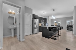 Modern kitchen featuring dark wood-finish cabinetry, stainless steel appliances, and a central island with a light-toned countertop - 