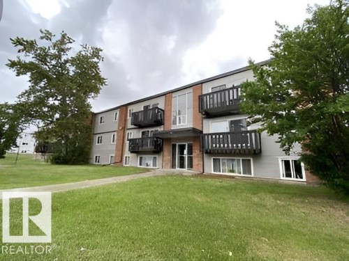 Multi-story building exterior featuring a gray and brick facade - 107 Village Acres Northwest, Edmonton, AB - Outdoor With Balcony