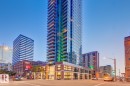 Modern high-rise residential building featuring extensive glass exterior, multiple balconies with glass railings, and a ground-level retail facade with large windows - 2902 10180 103 Street, Edmonton, AB 