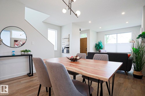 Open-concept main living area with wood-finish flooring, recessed lighting, and large windows - 12842 121 Street, Edmonton, AB 