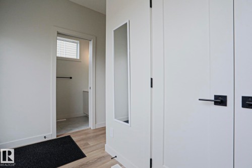 Hallway featuring light wood-finish flooring, white walls, and contemporary black hardware on doors - 12842 121 Street, Edmonton, AB 